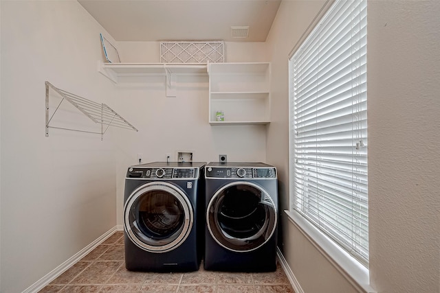 laundry room with washer and dryer, baseboards, and light tile patterned floors