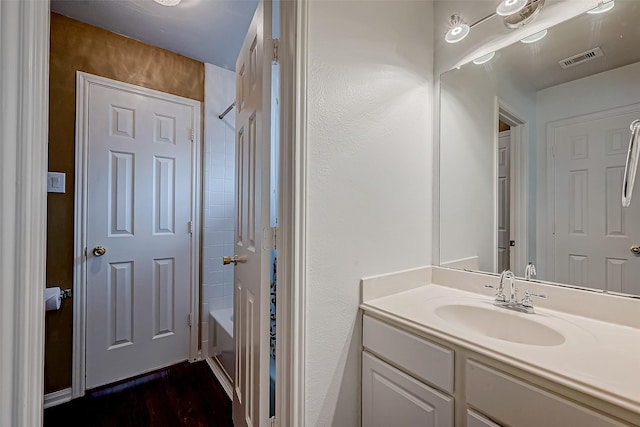 full bath featuring wood finished floors, vanity, and  shower combination