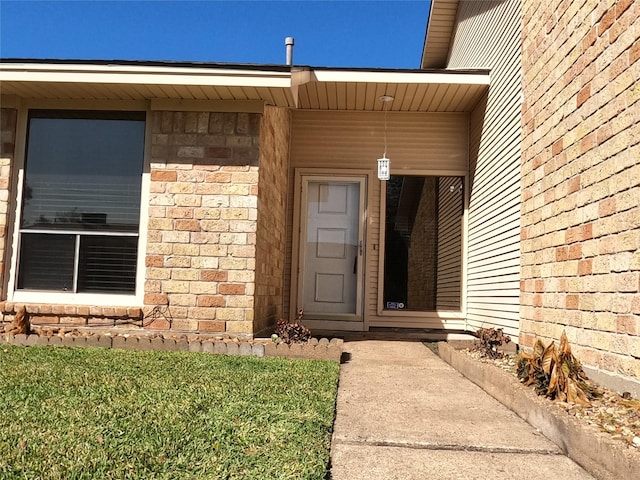 view of exterior entry with a yard