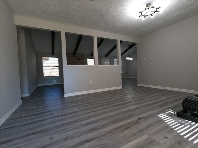 unfurnished living room with dark hardwood / wood-style flooring, a textured ceiling, and vaulted ceiling with beams