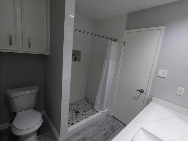 bathroom featuring vanity, toilet, curtained shower, and a textured ceiling