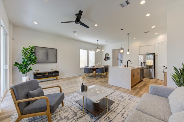 living room featuring sink, ceiling fan, and light wood-type flooring