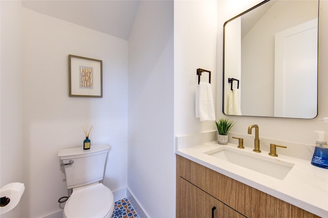 half bathroom featuring toilet, baseboards, and vanity