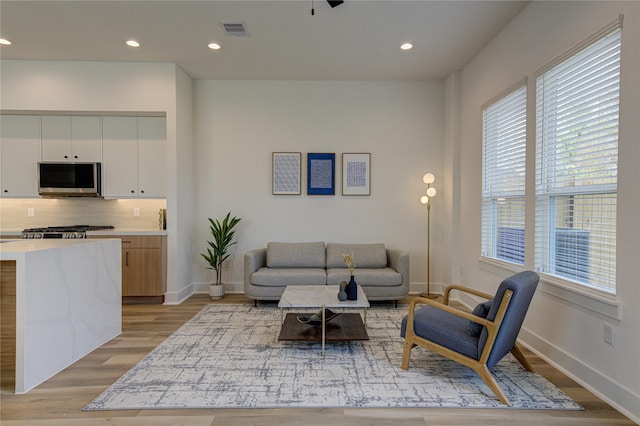 living room featuring light wood-style flooring, visible vents, baseboards, and recessed lighting