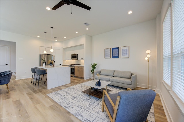 living area featuring recessed lighting, visible vents, light wood-style flooring, and baseboards