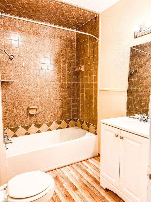 full bathroom featuring tiled shower / bath, wood-type flooring, toilet, and vanity