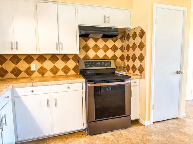 kitchen featuring electric range, tile countertops, white cabinets, and light tile patterned flooring