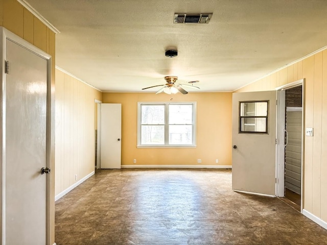 spare room featuring ceiling fan, ornamental molding, and wood walls