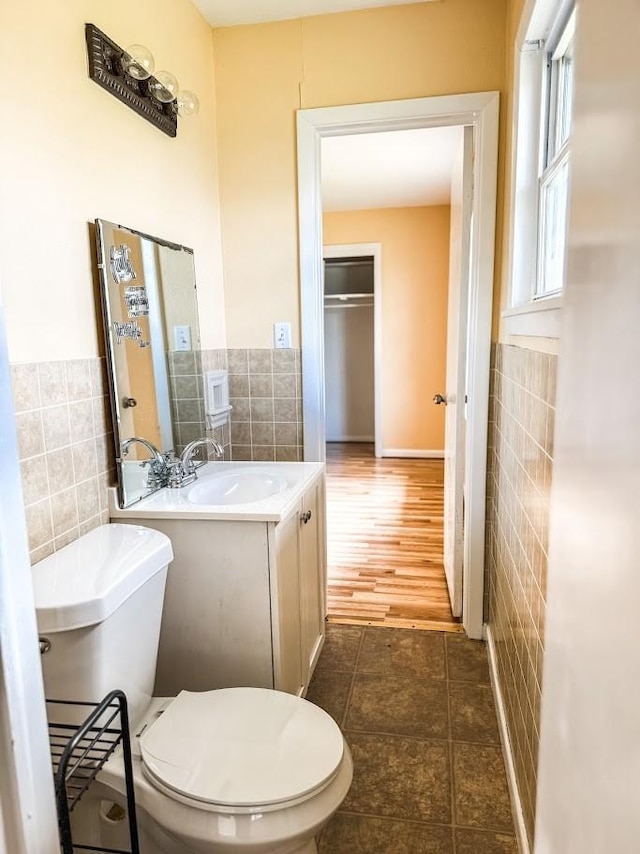 bathroom featuring tile patterned flooring, vanity, tile walls, and toilet