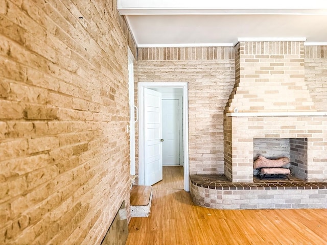 unfurnished living room featuring brick wall, hardwood / wood-style floors, and a brick fireplace