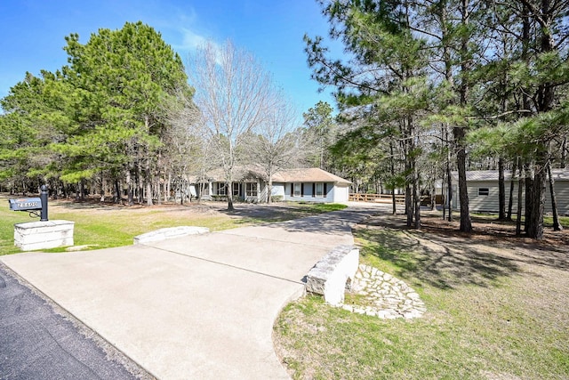 view of front facade featuring concrete driveway and a front lawn