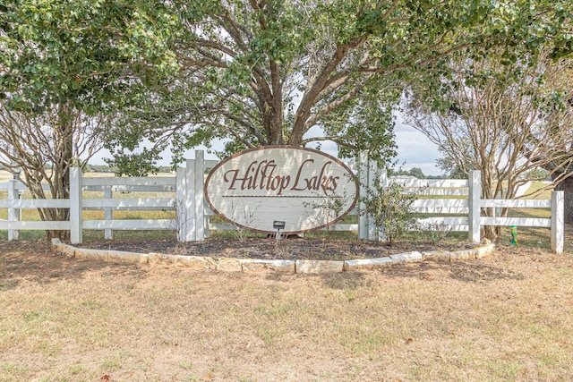 community / neighborhood sign featuring fence and a lawn