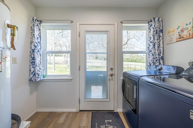 clothes washing area featuring laundry area, washer and clothes dryer, wood finished floors, and baseboards