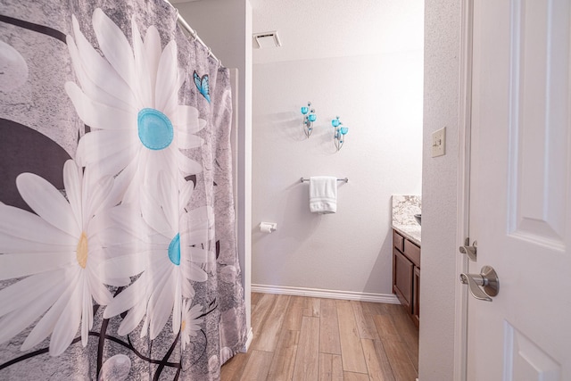 bathroom featuring visible vents, wood finished floors, vanity, and baseboards