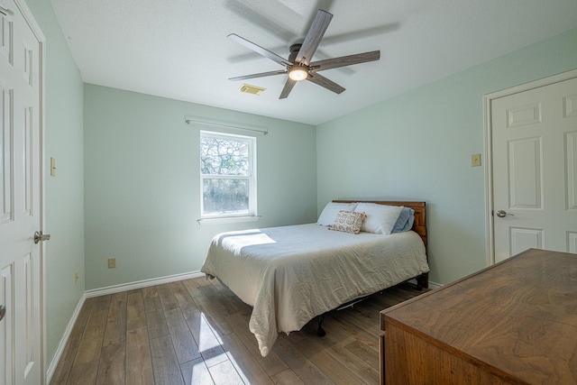 bedroom with dark wood-type flooring, visible vents, ceiling fan, and baseboards