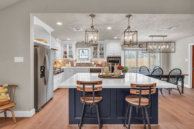 kitchen featuring hanging light fixtures, stainless steel appliances, white cabinets, and a kitchen island