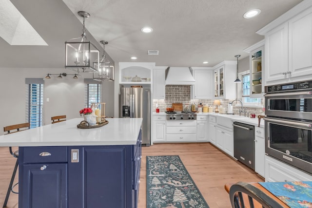 kitchen with pendant lighting, a kitchen breakfast bar, appliances with stainless steel finishes, and blue cabinets