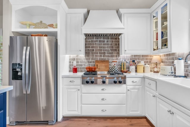 kitchen with sink, custom exhaust hood, white cabinets, stainless steel appliances, and backsplash