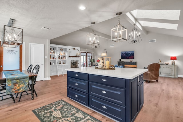 kitchen with pendant lighting, lofted ceiling with skylight, blue cabinetry, and a center island