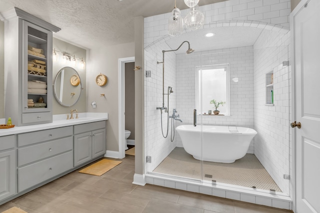 full bathroom featuring tile patterned floors, toilet, shower with separate bathtub, a textured ceiling, and vanity