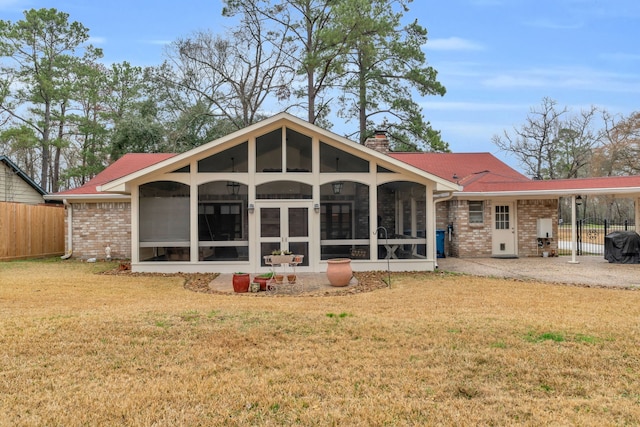 rear view of property featuring a lawn and a sunroom