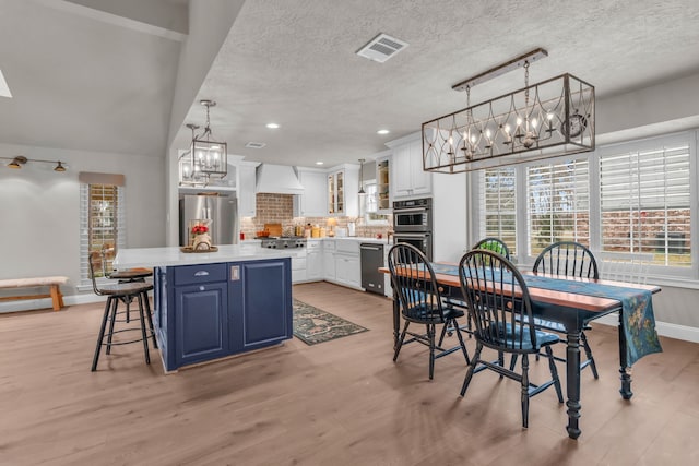 dining room with a notable chandelier, sink, a textured ceiling, and light hardwood / wood-style floors