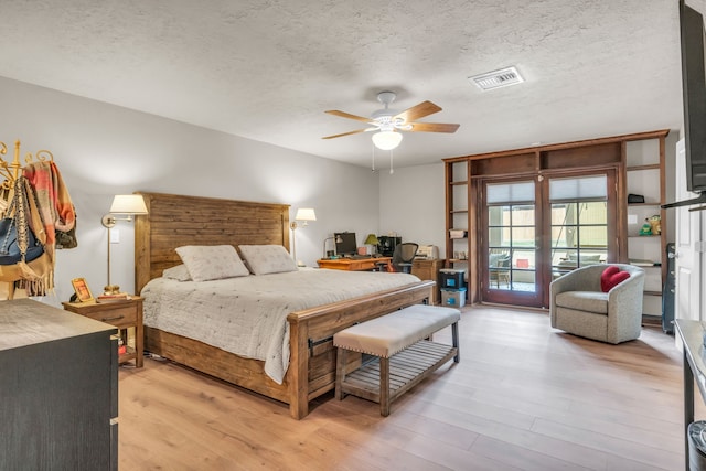 bedroom featuring access to outside, a textured ceiling, and light hardwood / wood-style flooring