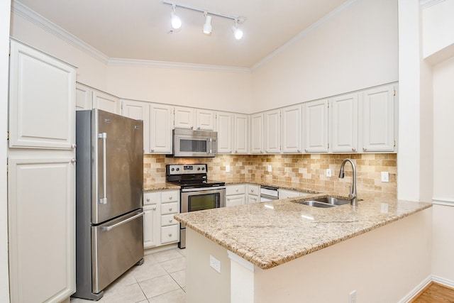 kitchen with appliances with stainless steel finishes, white cabinets, a sink, light stone countertops, and a peninsula