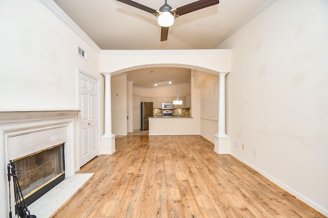 unfurnished living room featuring light wood-style flooring, a premium fireplace, visible vents, ornate columns, and crown molding