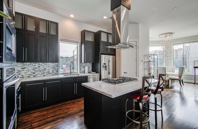 kitchen with glass insert cabinets, a kitchen island, appliances with stainless steel finishes, and a sink