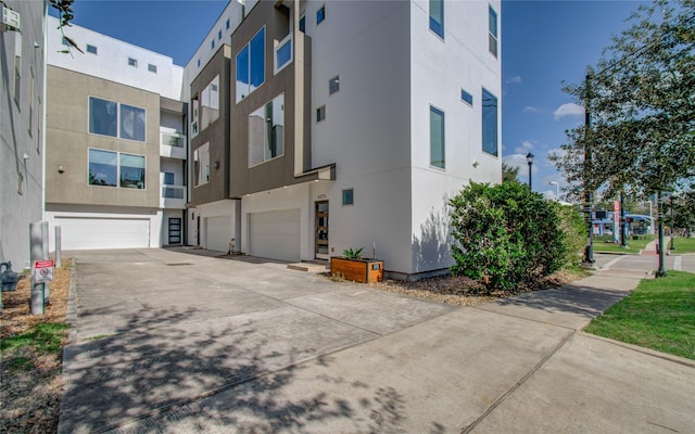 view of side of property featuring an attached garage and stucco siding