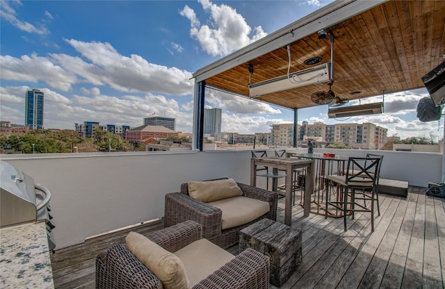 wooden deck with a view of city, outdoor lounge area, an outdoor bar, and grilling area