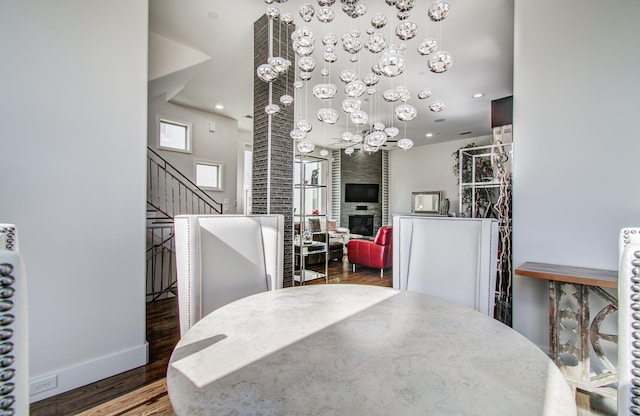 dining area featuring a large fireplace, baseboards, stairway, dark wood-type flooring, and recessed lighting