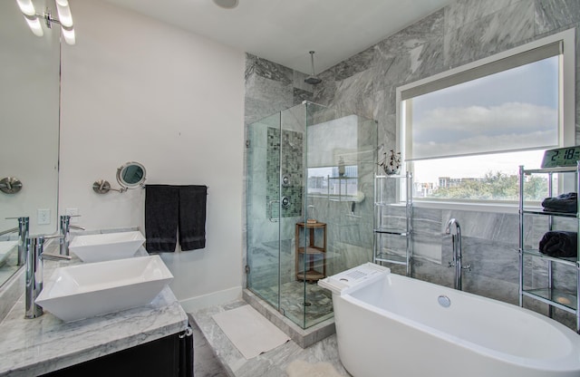 bathroom featuring double vanity, a stall shower, marble finish floor, a freestanding bath, and a sink