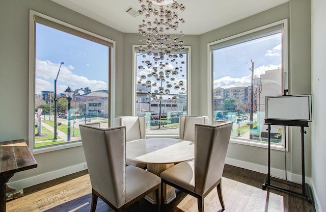 dining room featuring a healthy amount of sunlight, visible vents, baseboards, and wood finished floors