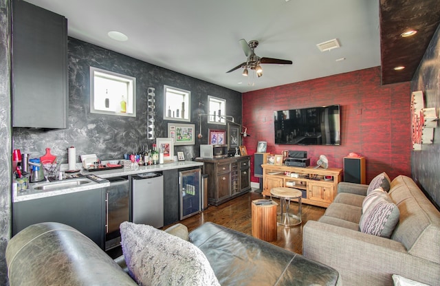 living area featuring dark wood-style floors, bar area, ceiling fan, beverage cooler, and wallpapered walls