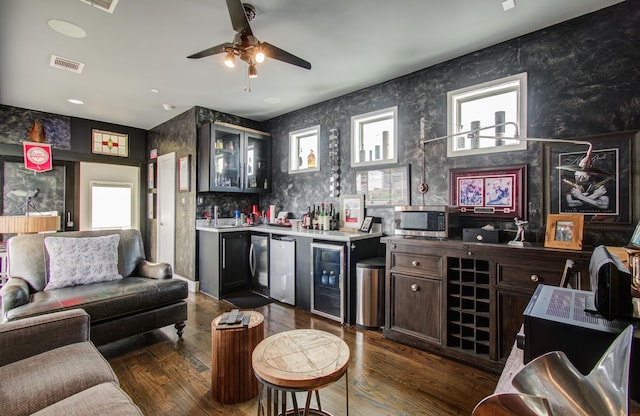 bar with visible vents, wet bar, stainless steel microwave, and dark wood-style flooring