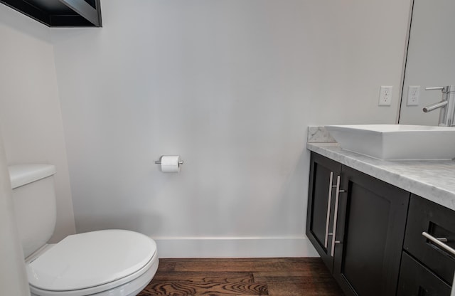 bathroom with toilet, baseboards, wood finished floors, and vanity