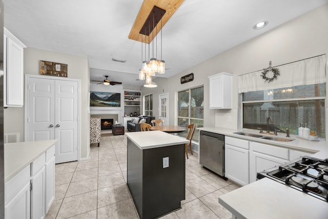 kitchen with dishwashing machine, sink, white cabinets, a kitchen island, and decorative light fixtures