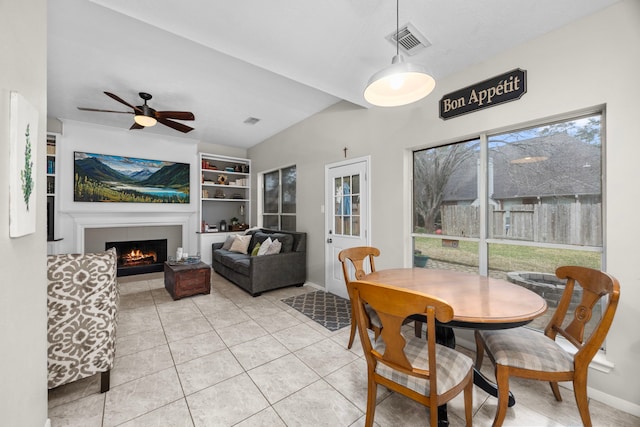 dining area with ceiling fan, a tile fireplace, and light tile patterned floors