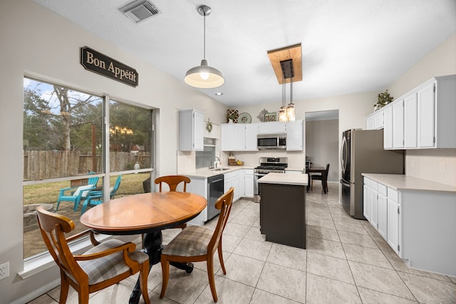 kitchen featuring sink, appliances with stainless steel finishes, a kitchen island, pendant lighting, and white cabinets