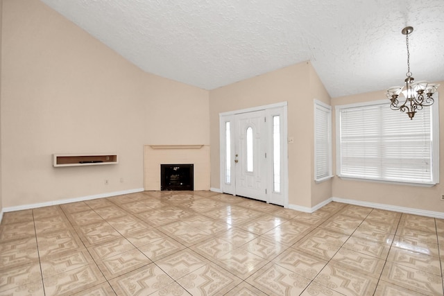 tiled entrance foyer with plenty of natural light, a chandelier, vaulted ceiling, and a textured ceiling