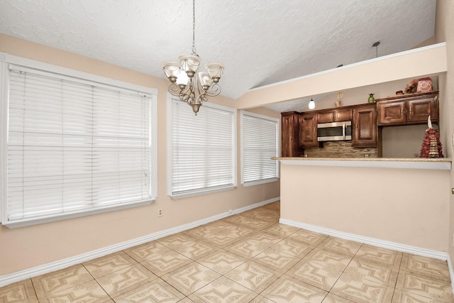 kitchen with vaulted ceiling, an inviting chandelier, decorative light fixtures, tasteful backsplash, and a textured ceiling