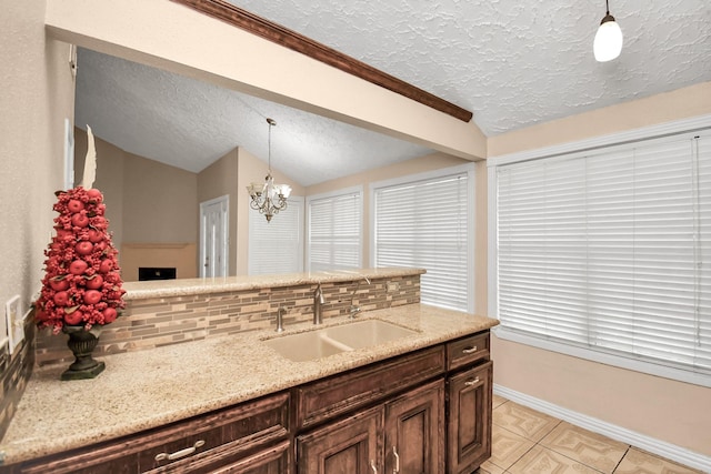 kitchen featuring tasteful backsplash, vaulted ceiling, sink, and pendant lighting