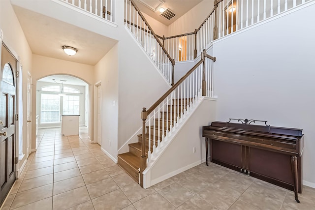 1408 S Friendswood Dr Unit 101, Friendswood, TX 77546 - tiled foyer featuring arched walkways, stairway, baseboards, and a towering ceiling