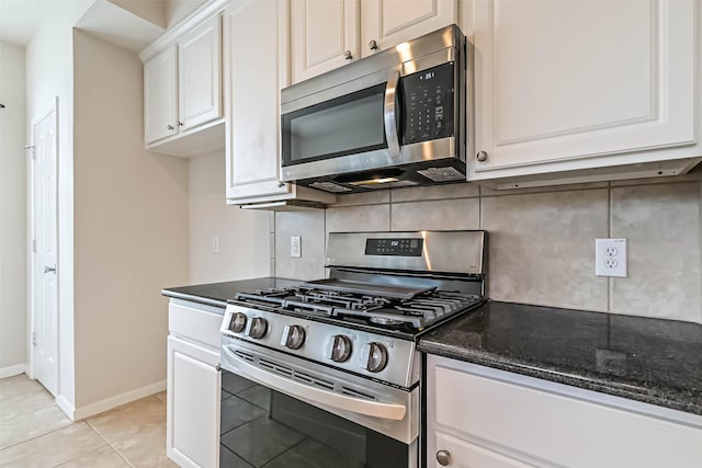 kitchen featuring white cabinetry, appliances with stainless steel finishes, dark stone countertops, and backsplash