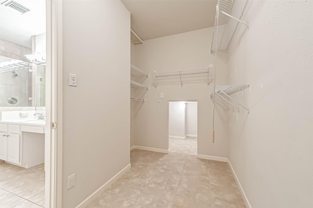 walk in closet featuring sink and light tile patterned floors