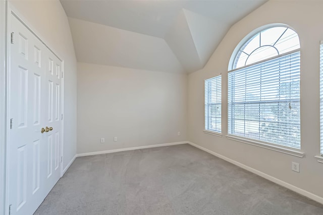 carpeted empty room with lofted ceiling