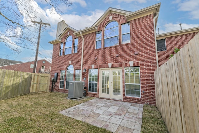 rear view of property featuring central AC unit, a yard, a patio area, and french doors