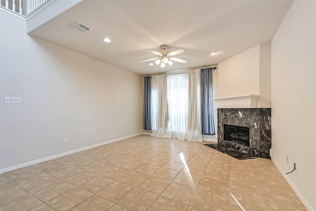 unfurnished living room featuring ceiling fan, a high end fireplace, and light tile patterned floors